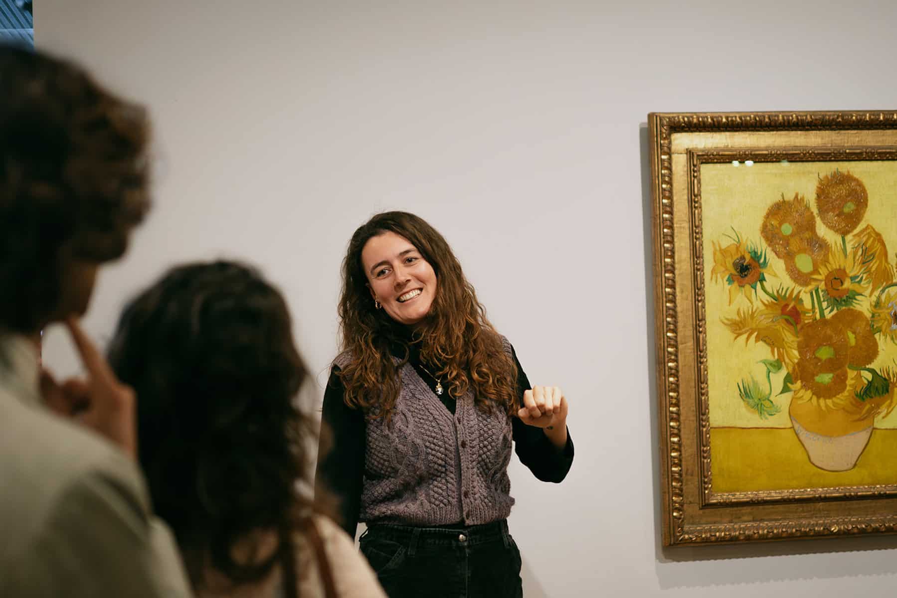 Woman discussing Van Gogh's Sunflowers in gallery.