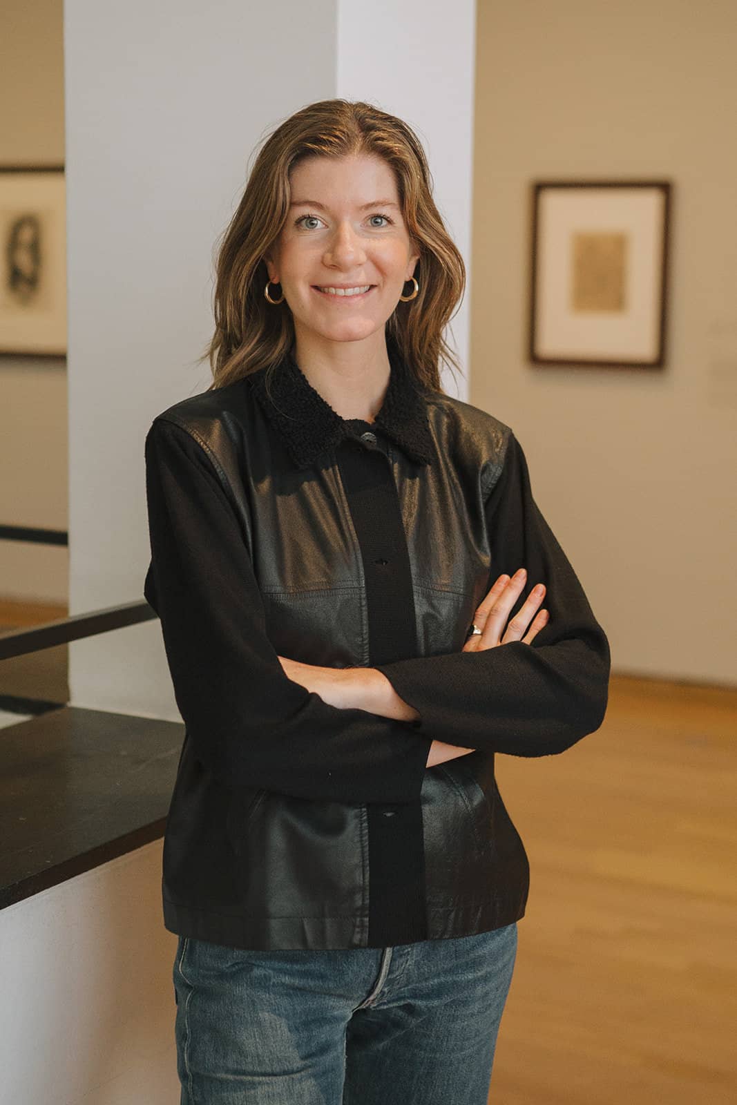 Woman in black jacket smiling in art gallery.