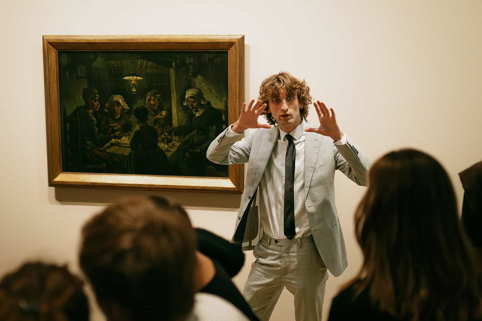 Man presenting historical painting to audience in gallery.