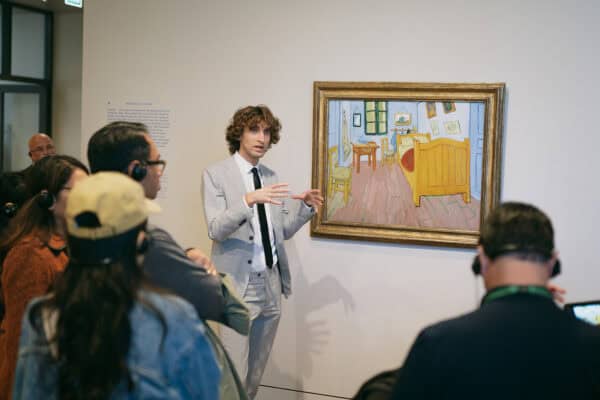 Guide explaining Van Gogh's painting to museum visitors.