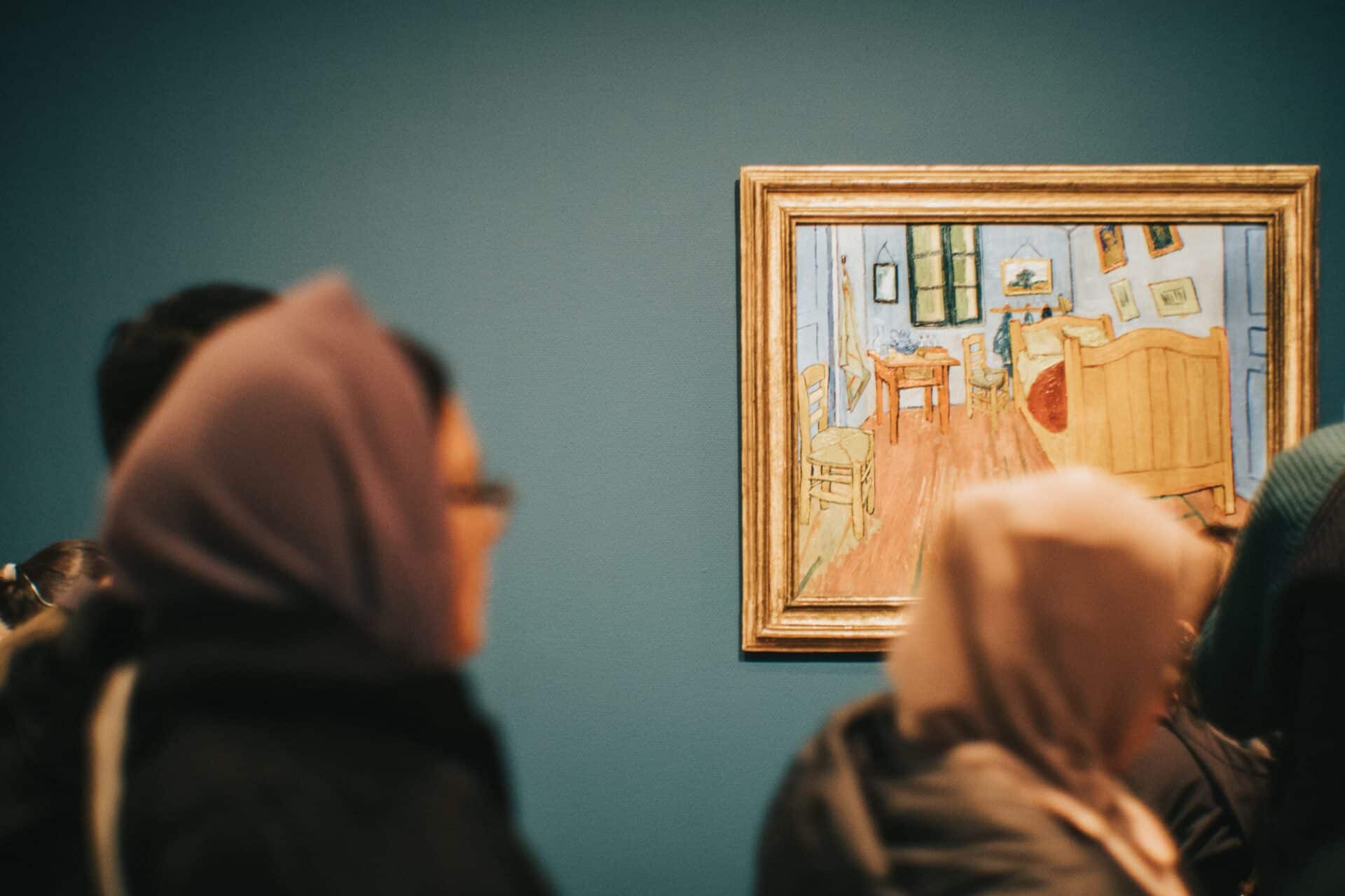 Visitors observing a framed painting in a gallery.